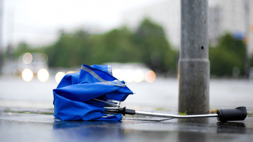 After a strong storm a broken umbrella is lying on the street