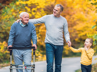 Elderly father adult son and grandson out for a walk in the park