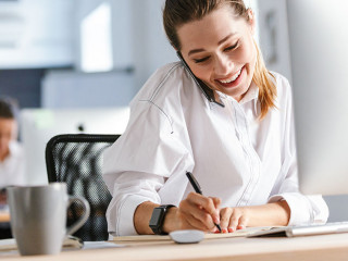 Cheerful young businesswoman sitting at her workplace