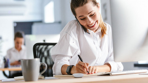 Cheerful young businesswoman sitting at her workplace