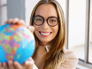 selbstbewusste junge frau mit brille hält einen globus in den händen