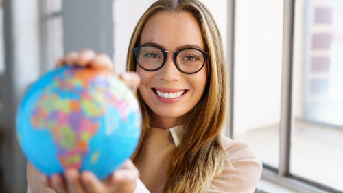 selbstbewusste junge frau mit brille hält einen globus in den händen