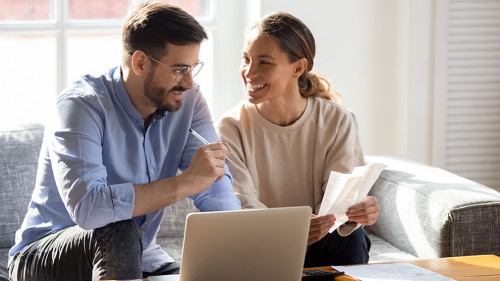 Happy young couple pay bills using online banking