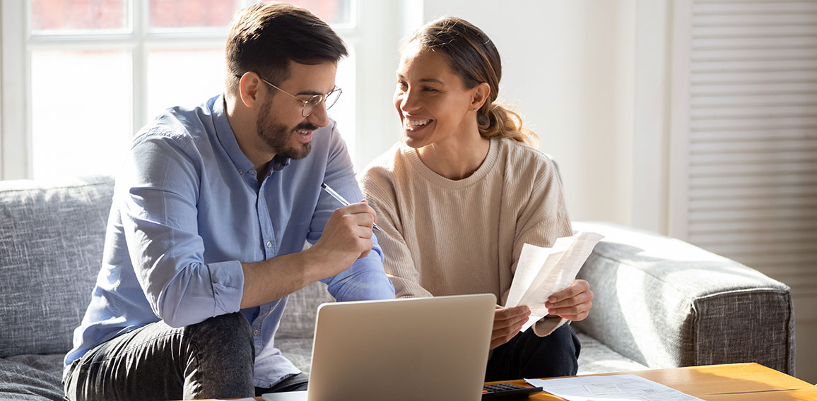 Happy young couple pay bills using online banking