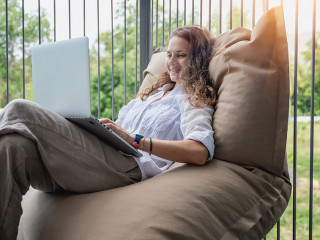 Happy beautiful young woman in a white shirt sits an bean bag c