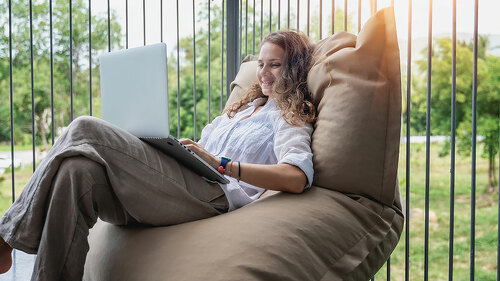 Happy beautiful young woman in a white shirt sits an bean bag c
