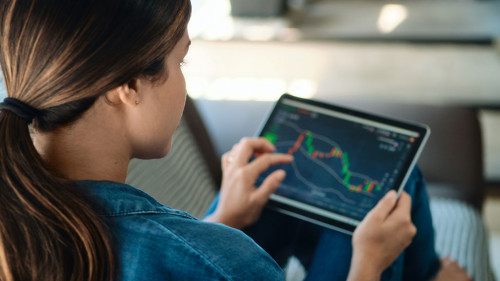 Woman Trading Online Using Tablet Computer On Sofa