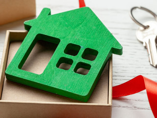 Gift box with red ribbon and house with keys. House as a gift