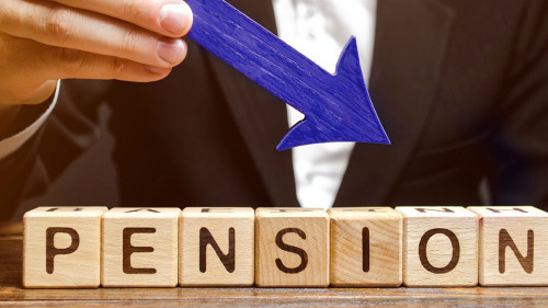 A man holds an arrow down over wooden blocks with the word Pension. Fall / reduction pension payments. Retirement. Financing retirees. Reduction of the pension fund. The low size of pensions.