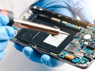 The technician repairing the smartphone's motherboard in the lab