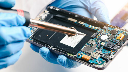 The technician repairing the smartphone's motherboard in the lab