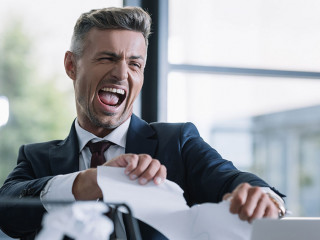 selective focus of irritated man tearing paper in office