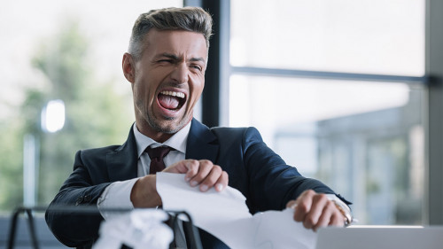 selective focus of irritated man tearing paper in office