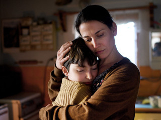 Portrait of sad poor mature mother hugging small daughter indoors at home, poverty concept.
