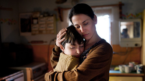 Portrait of sad poor mature mother hugging small daughter indoors at home, poverty concept.