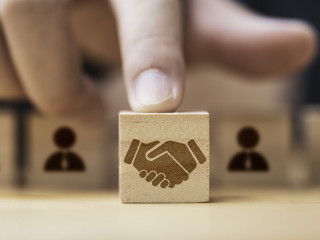 Hand putting hand shaking which print screen on wooden cube bloc