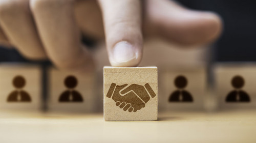 Hand putting hand shaking which print screen on wooden cube bloc