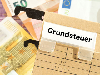 Euro Geldscheine und ein Ordner mit dem Aufdruck Grundsteuer
