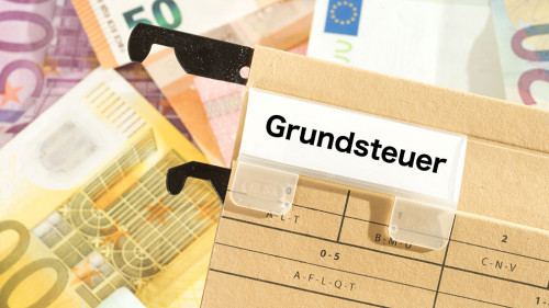 Euro Geldscheine und ein Ordner mit dem Aufdruck Grundsteuer