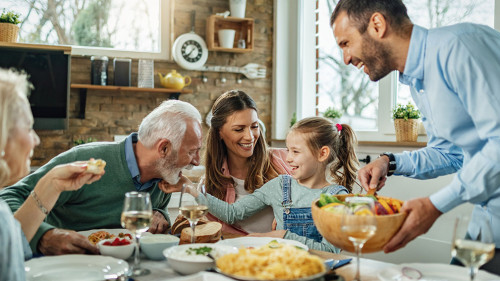 Happy extended family having fun during family lunch in dining room.