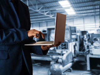 Manager Industrial Engineer in the suit uses Laptop Computer wit