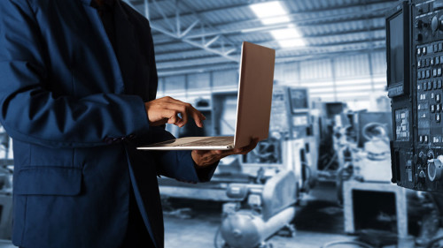 Manager Industrial Engineer in the suit uses Laptop Computer wit