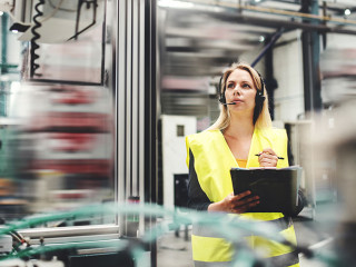 Industrial woman engineer with headset in a factory, working. Copy space.
