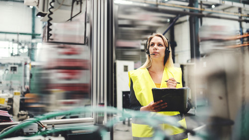 Industrial woman engineer with headset in a factory, working. Copy space.