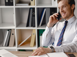 Relaxed man talking on the phone at work and smiling