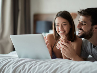 Man and woman at home surfing the net in bed