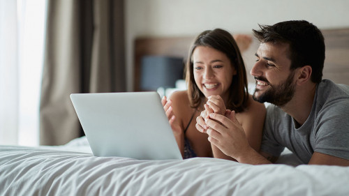 Man and woman at home surfing the net in bed