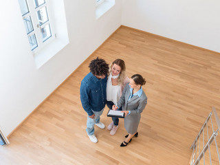 Junges Paar mit Immobilienmaklerin bei Besichtigung einer Mietwo