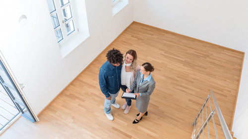 Junges Paar mit Immobilienmaklerin bei Besichtigung einer Mietwo