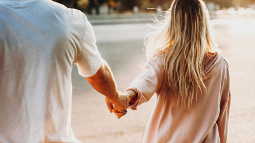 Crop couple holding hands on street