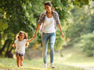 Mother and daughter playing and running around the park on beaut