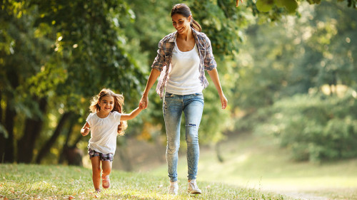 Mother and daughter playing and running around the park on beaut
