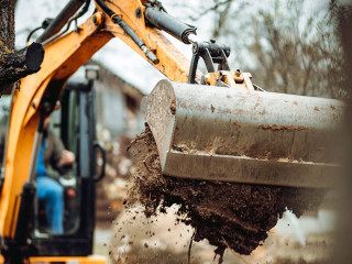 Worker using excavator and bulldozer for landscaping works