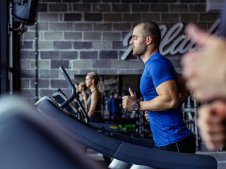 Young man in sportswear running on treadmill at gym.