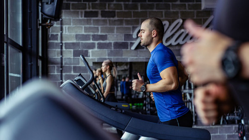 Young man in sportswear running on treadmill at gym.