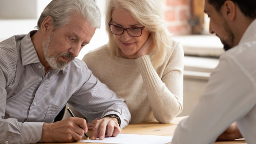 Happy mature couple close deal signing contract with realtor