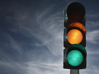 Semaforo sullo sfondo del cielo con luci gialla e verde accese,