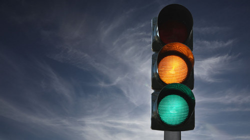Semaforo sullo sfondo del cielo con luci gialla e verde accese,