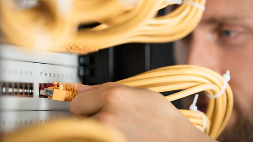 Engineer Plugging Cables Into Server