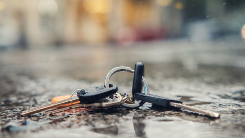 Set of lost keys on the ring on wet ground on the street