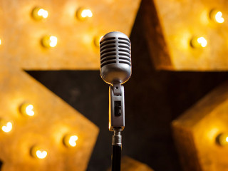 Microphone on theater or karaoke stage, golden luminous star on background