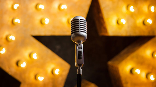 Microphone on theater or karaoke stage, golden luminous star on background