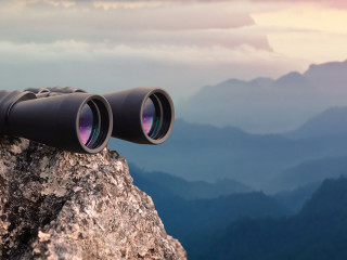 Binocular on top of rock mountain at sunset