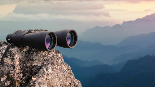 Binocular on top of rock mountain at sunset