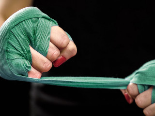 Woman is wrapping hands with pink boxing wraps
