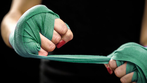 Woman is wrapping hands with pink boxing wraps